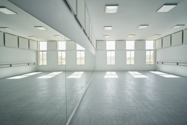 Vista interior de un aula de danza con el reflejo de la misma en el espejo